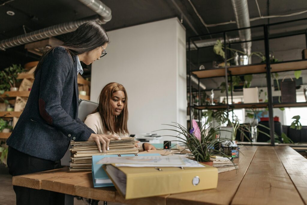employees with stack of files on desk