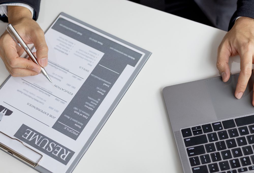 reviewing a resume with a laptop near by